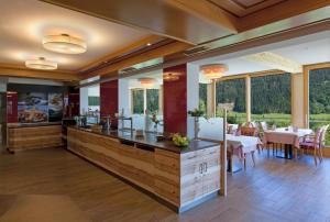 a restaurant with a dining room with tables and windows at Hotel Nagglerhof am Weissensee in Weissensee