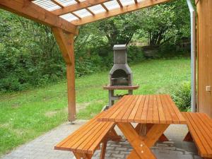 una mesa de picnic y una parrilla bajo una pérgola de madera en Chata Koutík en Loučná nad Desnou
