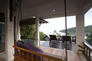 a porch with a swing with a view of the water at Salad Buri Resort- SHA Extra Plus in Salad Beach