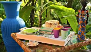 a tray with a cake and cups and a blue vase at Nirvana Beach Hotel in Barra Grande
