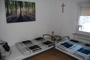 a bedroom with two beds and a cross hanging on the wall at 6 Schulstraße in Bieber
