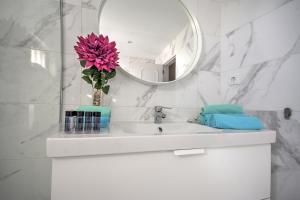 uma casa de banho com um lavatório com um vaso com uma flor rosa em In Faro with Sea View em Faro mais 36 fotografias