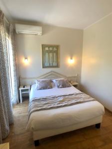 1 dormitorio con 1 cama blanca grande y 2 almohadas en Hôtel Méditerranée, en Le Lavandou