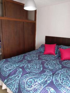 1 dormitorio con 1 cama con 2 almohadas rosas en departamento con vista al mar, en Valparaíso