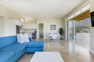 a living room with a blue couch and a kitchen at Mount Bay in Hout Bay