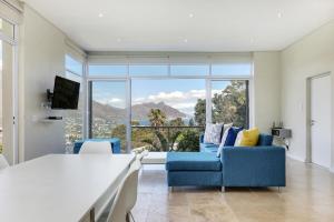 a room with a large bed and two blue chairs at Mount Bay in Hout Bay