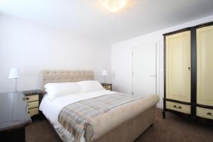 a white bedroom with a bed and a dresser at Friars House, Stafford by BELL Apartments in Stafford