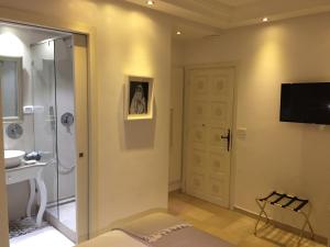 a bathroom with a shower and a television on a wall at Dar Corniche La Marsa (Adults Only) in La Marsa