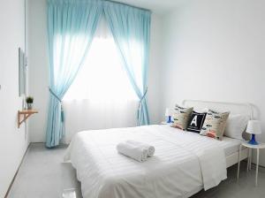 Schlafzimmer mit einem weißen Bett und blauen Vorhängen in der Unterkunft Seaview Akelinee Apartment 3 in Kuala Terengganu