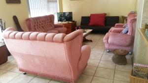uma sala de estar com cadeiras cor-de-rosa e um sofá em Beth-El em Mossel Bay