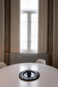 una mesa blanca con un tazón delante de una ventana en Sunday - Alda's Vintage Apartments with Free Parking en Oporto