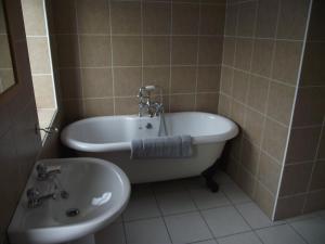 
a bath tub sitting next to a sink in a bathroom at Poolewe Hotel in Poolewe

