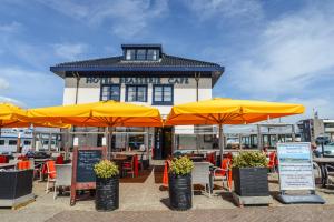 a seafood restaurant with orange umbrellas in front of it at Havenhotel At Sea Texel in Oudeschild