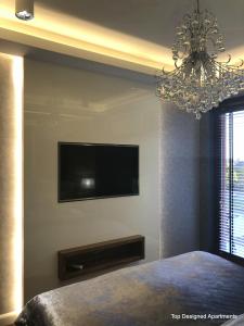 1 dormitorio con TV y lámpara de araña en Top Designed Apartments en Gdansk