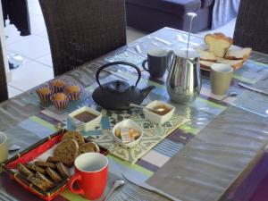a table with a tray of bread and a tea kettle at Chambres d'hôtes à Raveau in Raveau