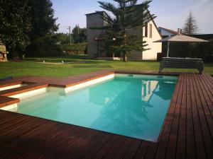 a swimming pool with a wooden deck and a house at La Curia in Pontevedra