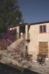 a stone building with a staircase and a table and bench at La Curia in Pontevedra