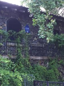 a stone building with a blue sign on a fence at Aprisa apartment in Piedimonte Etneo