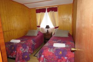 een slaapkamer met twee bedden en een raam bij Departamentos Emanuel in Chaitén +27 foto's