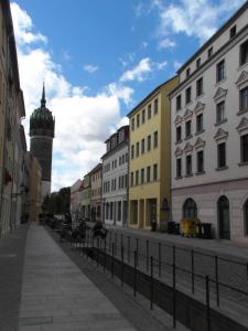 een stadsstraat met gebouwen en een klokkentoren bij Appartement Luthers Stübchen in Lutherstadt Wittenberg