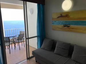a living room with a couch and a balcony at Apartamentos do Mar Funchal in Funchal +103 photos