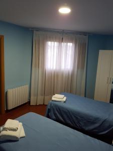 a bedroom with two beds and a window with towels at HOSTAL ITXASO-ENEA in Aoiz