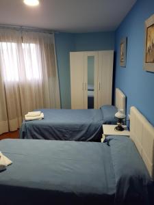 2 Betten in einem Zimmer mit blauen Wänden in der Unterkunft HOSTAL ITXASO-ENEA in Aoiz