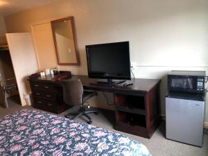 a hotel room with a desk with a television and a bed at Midtown Inn in Springfield