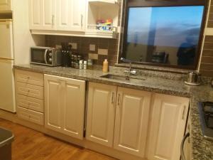 a kitchen with white cabinets and a sink and a window at Helens Self Catering in Castlebar