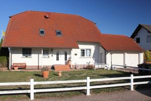 une maison blanche avec un toit orange et une clôture dans l'établissement Ruhige und gemütliche Ferienwohnung in Calden, à Calden