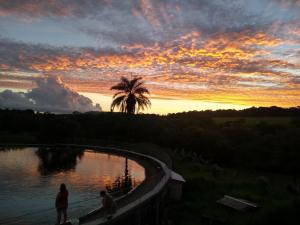 two people walking on a bridge over a river at sunset at Hotel farol de Minas in Alpinópolis