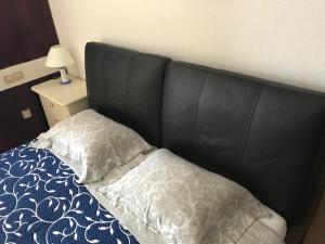 a bed with a black head board and two pillows at Apartamentos do Mar Funchal in Funchal