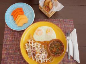 a yellow plate of food with an egg and carrots at Casa Mayoral B&B Pet friendly in Valle de Guadalupe