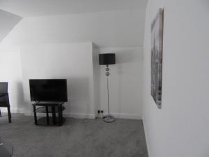 a living room with a television and a lamp at No 6 AT 19 IVANHOE - LARGE 2 BED NEAR SEFTON PARK AND LARK LANE in Liverpool