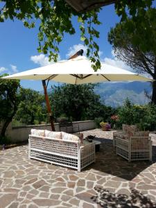 una sombrilla blanca y sillas en el patio en Agriturismo Persichitti en Torricella Peligna