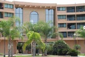 a large building with palm trees in front of it at Caesarea Vacation Rooms in Caesarea
