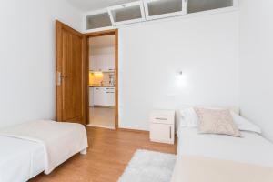 a white bedroom with two beds and a kitchen at Apartments Bezmalinović 2 in Bol +32 photos