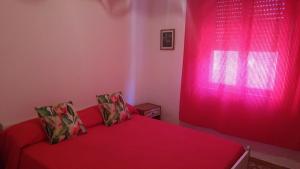 イーゾラ・ロッサにあるFronte Mareのピンクの窓、赤いベッドが備わるベッドルーム1室が備わります。