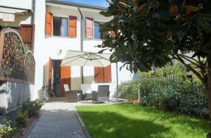 a patio with a table and an umbrella in a yard at CaMagnolia Apartment in Montegrotto Terme