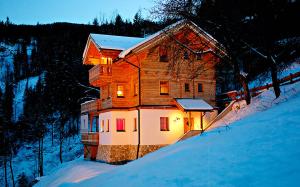 a wooden house in the snow at night at Chalet4You in Haus im Ennstal +25 photos