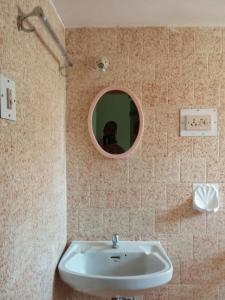 a bathroom with a sink and a round mirror at J & B Holiday Homes in Benaulim