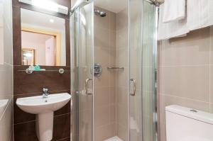 uma casa de banho com um chuveiro, um lavatório e um WC. em Rose Park Hotel em Londres