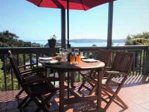 a wooden table with chairs and an umbrella on a balcony at Paradise Views Luxury 2BR Apartment in Paihia