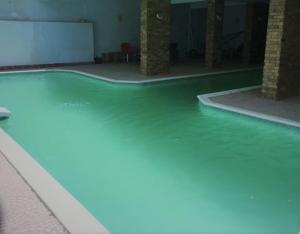 a swimming pool with green water in a building at A studio / private room in New Cairo in Cairo