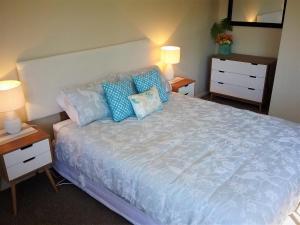 a bedroom with a large bed with blue pillows at Paradise Views Luxury 2BR Apartment in Paihia