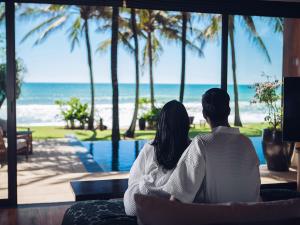 um casal sentado num sofá a olhar para o oceano em Villa Nandana by Elite Havens em Praia de Natai