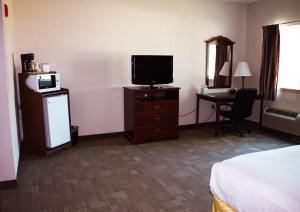Cette chambre comprend un lit, une télévision et un bureau. dans l'établissement Americas Best Value Inn-Fredonia, à Fredonia