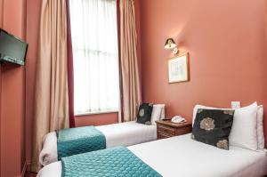 a hotel room with two beds and a window at The Coronation Hotel in London