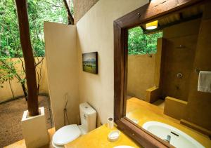 bagno con lavandino, servizi igienici e specchio di Back of Beyond - Pidurangala a Sigiriya