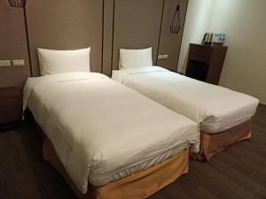 2 bedden in een hotelkamer met witte lakens bij O2 Hotel Taipei Main Station in Taipei
